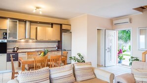 A modern kitchen with a dining area, a sofa with patterned cushions, and a view of the outdoors.