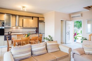 Eine moderne Küche mit Essbereich, einem Sofa mit gemusterten Kissen und Blick ins Freie.