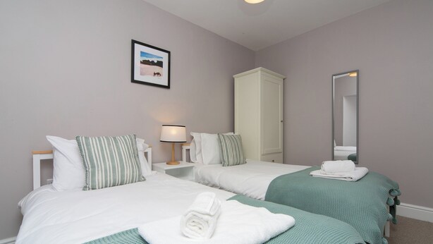 Una habitación de hotel con dos camas, un armario, un espejo y un cuadro en la pared.