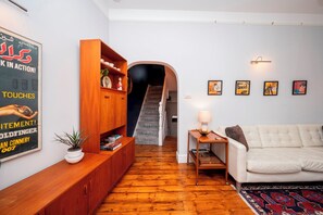 Un saló amb un sofà, un armari de fusta i una escala que mena a una altra habitació.