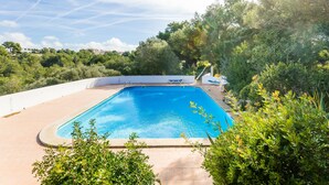 A rectangular swimming pool with a clear blue water surface, surrounded by a white wall and lush greenery. - Bouganville Apartment in Son Bou with Sea View (ALAIOR)