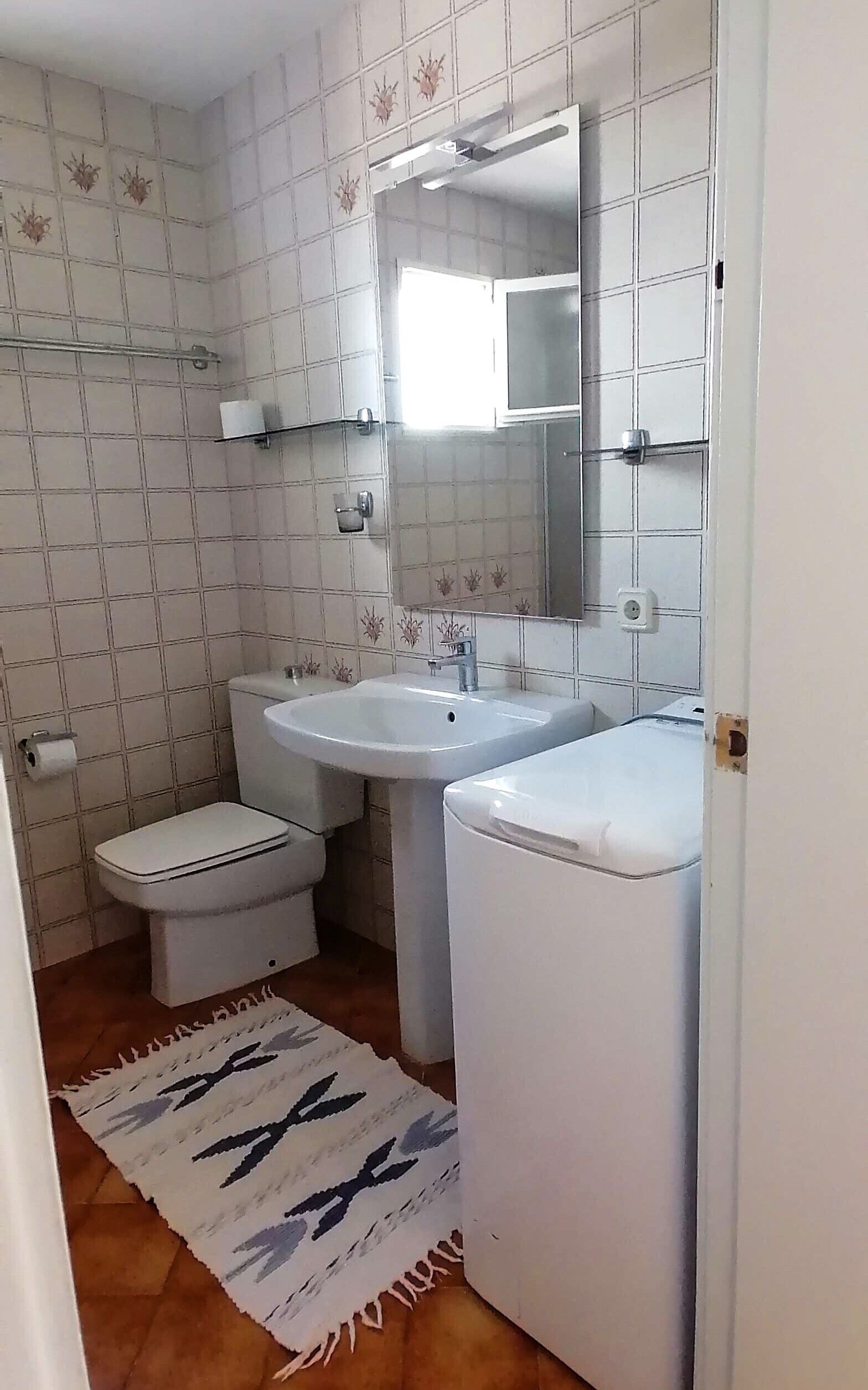 Een badkamer met toilet, wastafel en spiegel.