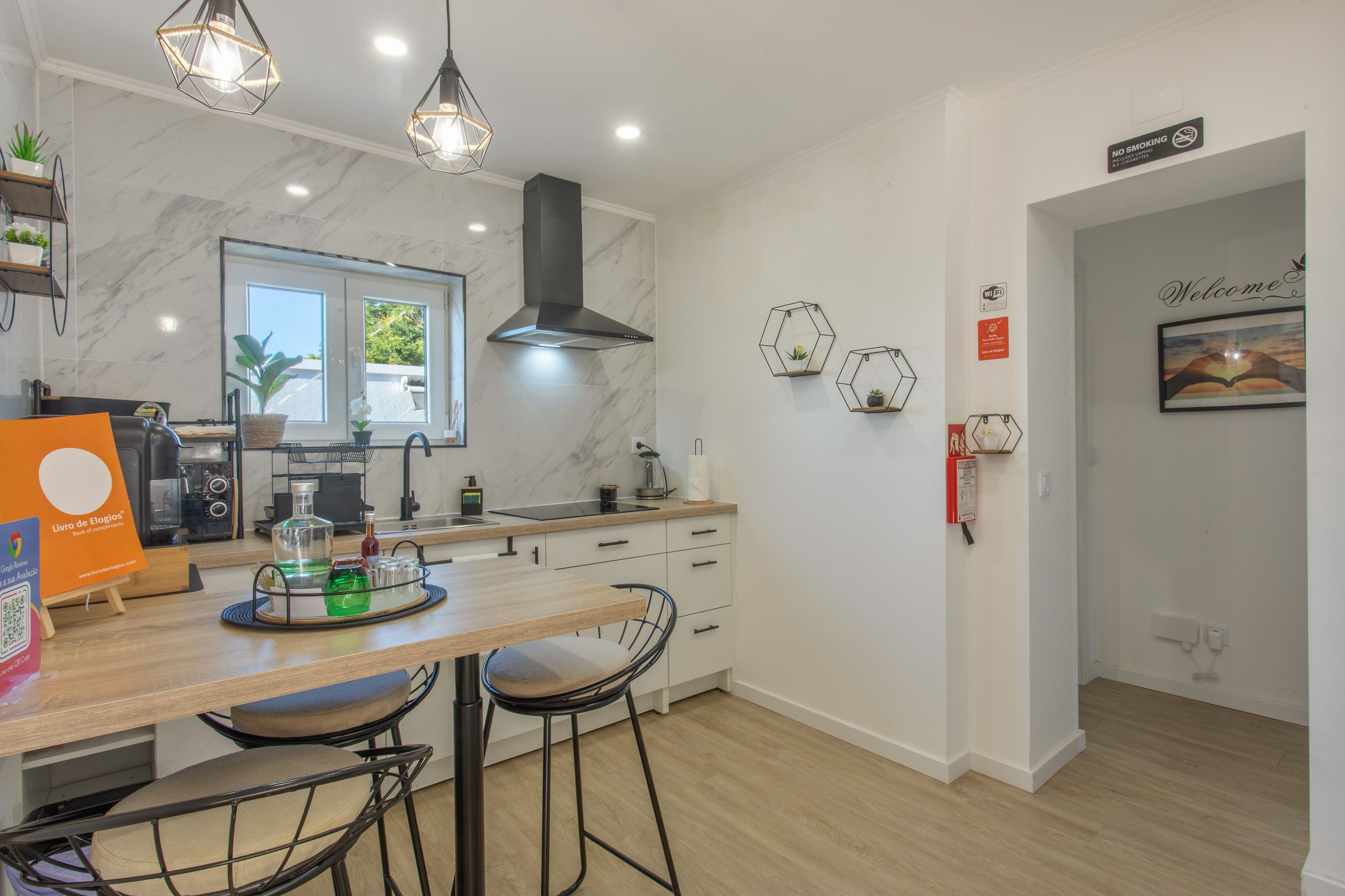 A modern kitchen with a marble backsplash, pendant lights, and a view of the outdoors.