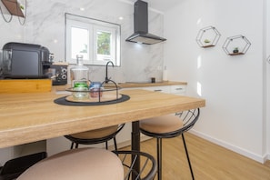 Une cuisine moderne avec une table en bois, des tabourets de bar, un four encastré et une hotte noire.