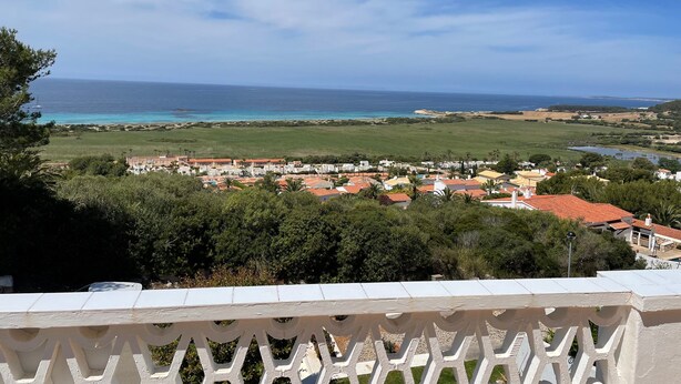 A coastal town with a view of the sea, green fields, and buildings with red roofs. - NiceView Apartment in Son Bou with Sea View – Ideal for Couples (ALAIOR)