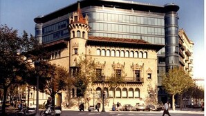 Ein historisches Gebäude mit einem modernen Glasanbau, das traditionelle und zeitgenössische Architektur vereint.