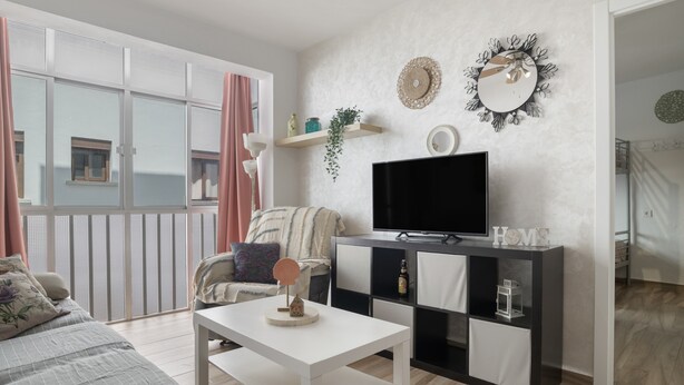 Un salon moderne doté d’un téléviseur à écran plat, d’une table basse blanche, d’un canapé et d’un balcon offrant une vue agréable.
