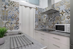 A kitchen with patterned tiles, a stainless steel sink, a microwave, and a drying rack. - 'Vista Mar Conil' Apartment with Sea Views, Shared Terrace and Wi-Fi (Conil de la Frontera)