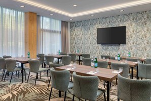 A conference room with tables, chairs, a flat-screen TV, and a patterned wall. - Spaarnwoude Park Hotel (Velsen-Zuid)