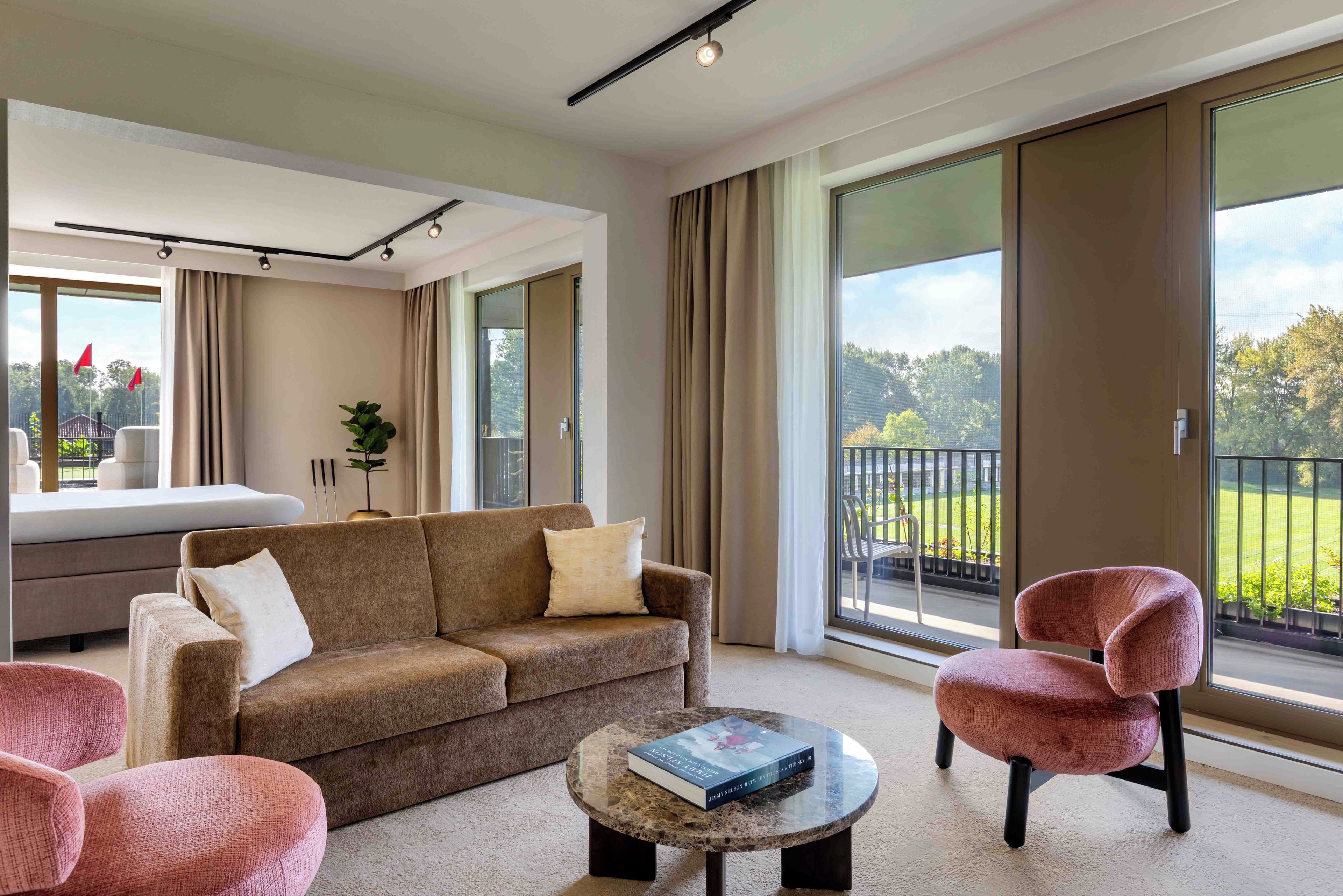 A modern living room with a sofa, armchairs, a coffee table, and a balcony with a view.