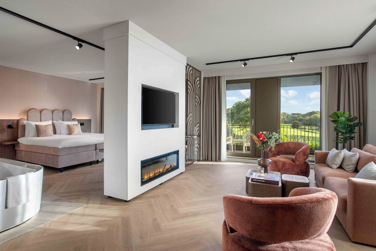 A modern living room with a fireplace, a sofa, a TV, and a view of the outdoors.