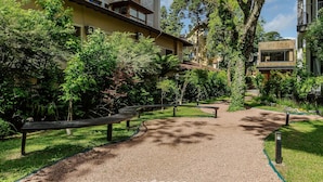 A pathway leading to a building with a garden area, benches, and a pergola. - Modern and Complete Stays in Gramados Tourist Center - Cbgs (Gramado)