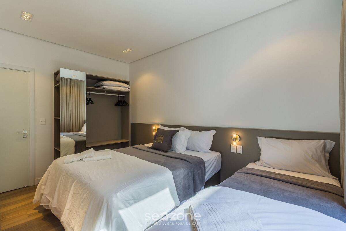Une chambre d’hôtel avec deux lits, une armoire et un miroir.