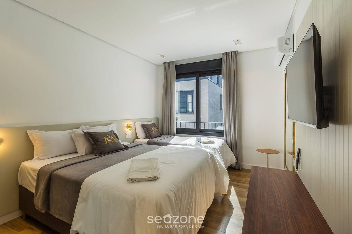 Une chambre d’hôtel moderne équipée de deux lits, d’un téléviseur à écran plat et d’une petite table.