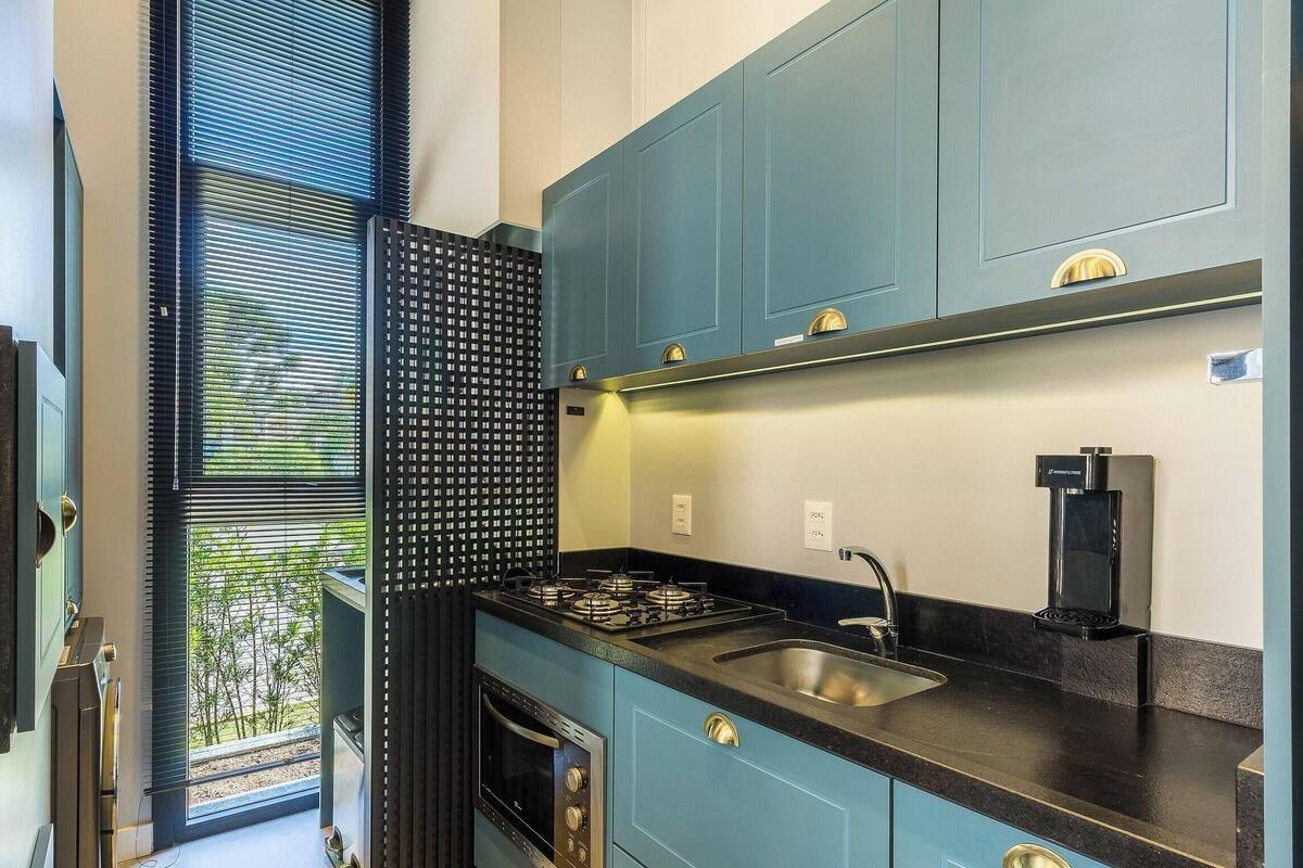 Une cuisine compacte avec des meubles bleus, une cuisinière à gaz, un évier et une machine à café.