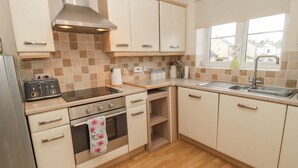 A compact kitchen with a stove, oven, and a single sink. - Ramblers Cottage (Alnwick)