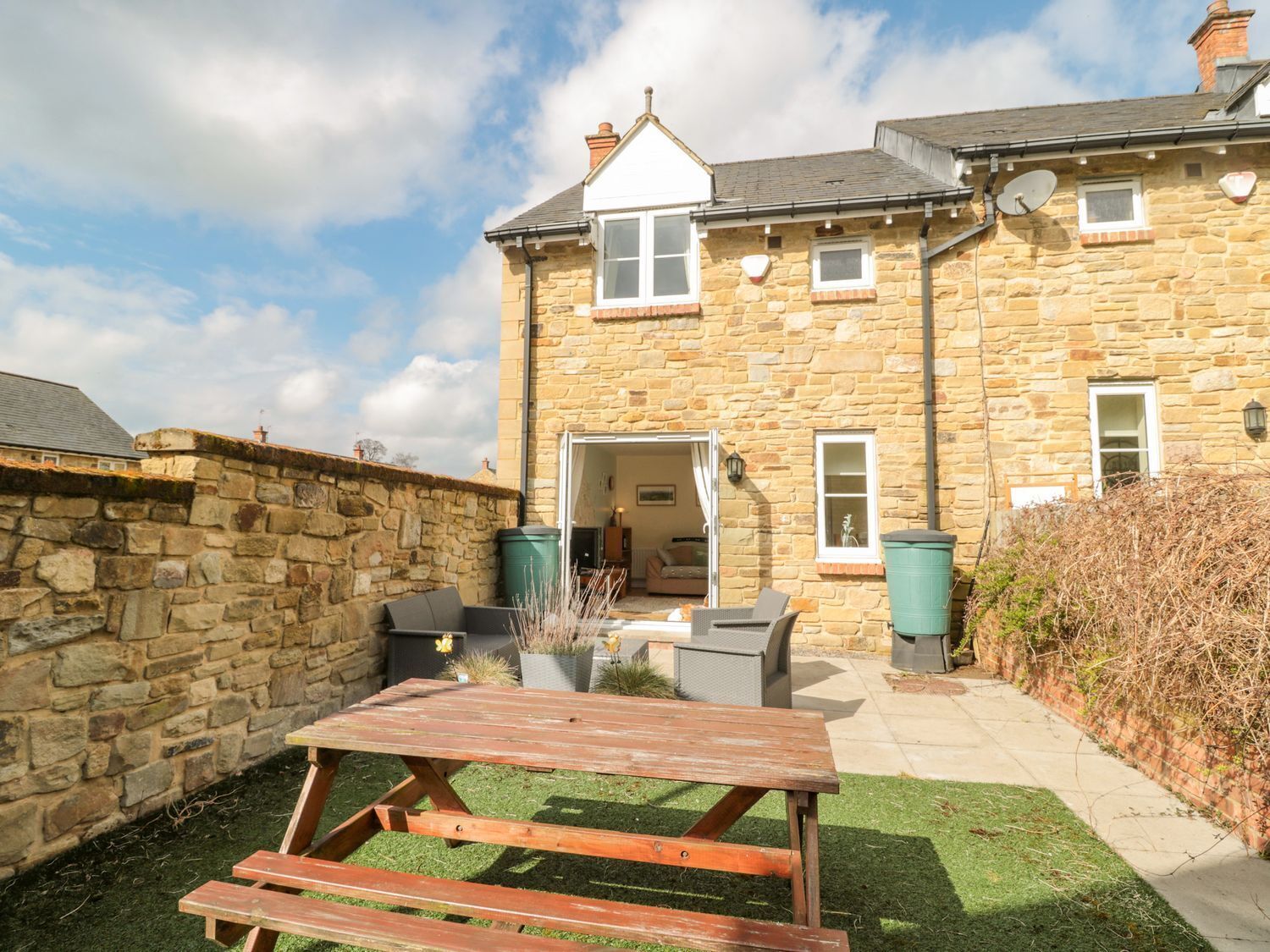 A stone house with a patio area, a wooden table, and outdoor seating.