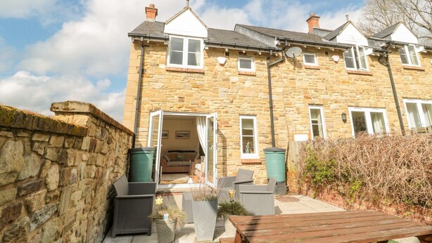 A stone building with a patio area, outdoor seating, and a view of the sky. - Ramblers Cottage (Alnwick)
