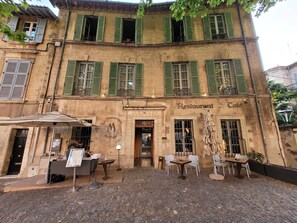 A building with a restaurant named 'Le Moutardier du Pope' on the ground floor, featuring outdoor seating with tables and chairs. - A Nest on the Roofs   (Avignon)