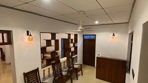 A hotel lobby with a reception desk, wooden chairs, a ceiling fan, and wall-mounted light fixtures. - Sweden Villa Galle (Galle)
