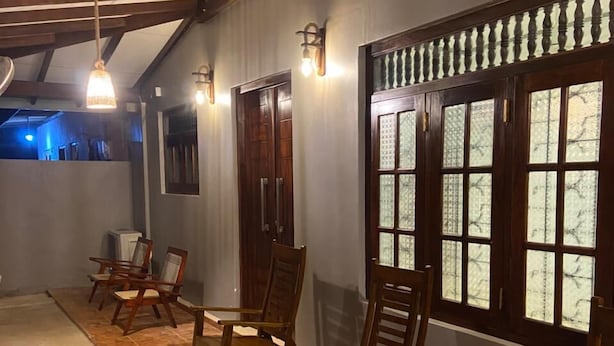 A hallway with wooden chairs, a door, and a window with frosted glass. - Sweden Villa Galle (Galle)