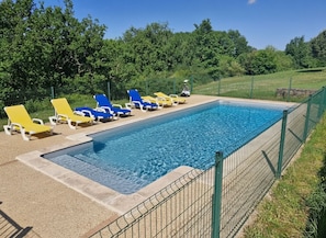 Ein rechteckiger Swimmingpool, umgeben von einem grünen Zaun.