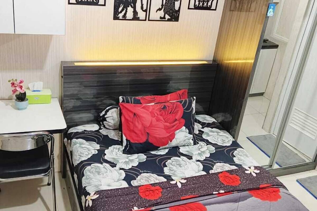 A bedroom with a bed, a bedside table, and a chair. There are wall decorations above the bed.