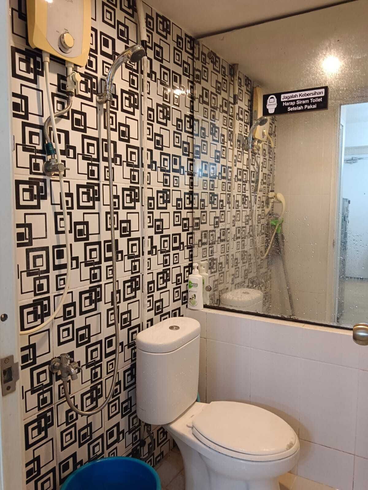 A bathroom with a toilet, a shower, and a hand dryer.