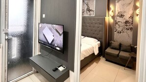 Ein modernes Hotelzimmer mit Fernseher, einem Bett, einer Couch und einer Wanddekoration.