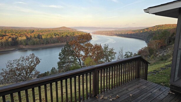 A wooden deck overlooking a river with autumn foliage and distant hills.