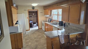 A kitchen with wooden cabinets, a refrigerator, a stove, a sink, and a coffee maker.