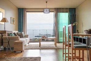 A modern living room with a sofa, a coffee table, and a view of the sea through large windows. - Glowing Funchal Apartment (Funchal)