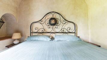 Ein Bett mit Metallkopfteil, einer Lampe und einer Wand mit einem Rundbogenfenster.