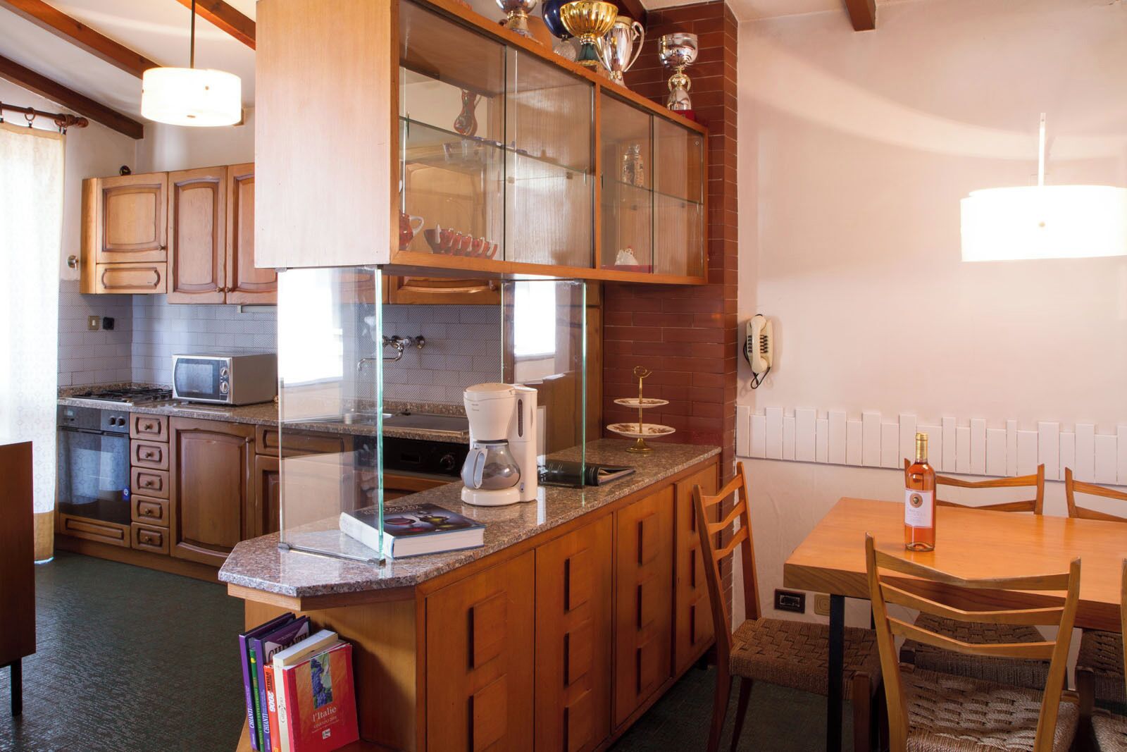 Une cuisine avec des meubles de rangement en bois, une machine à café et une table à manger avec des chaises.
