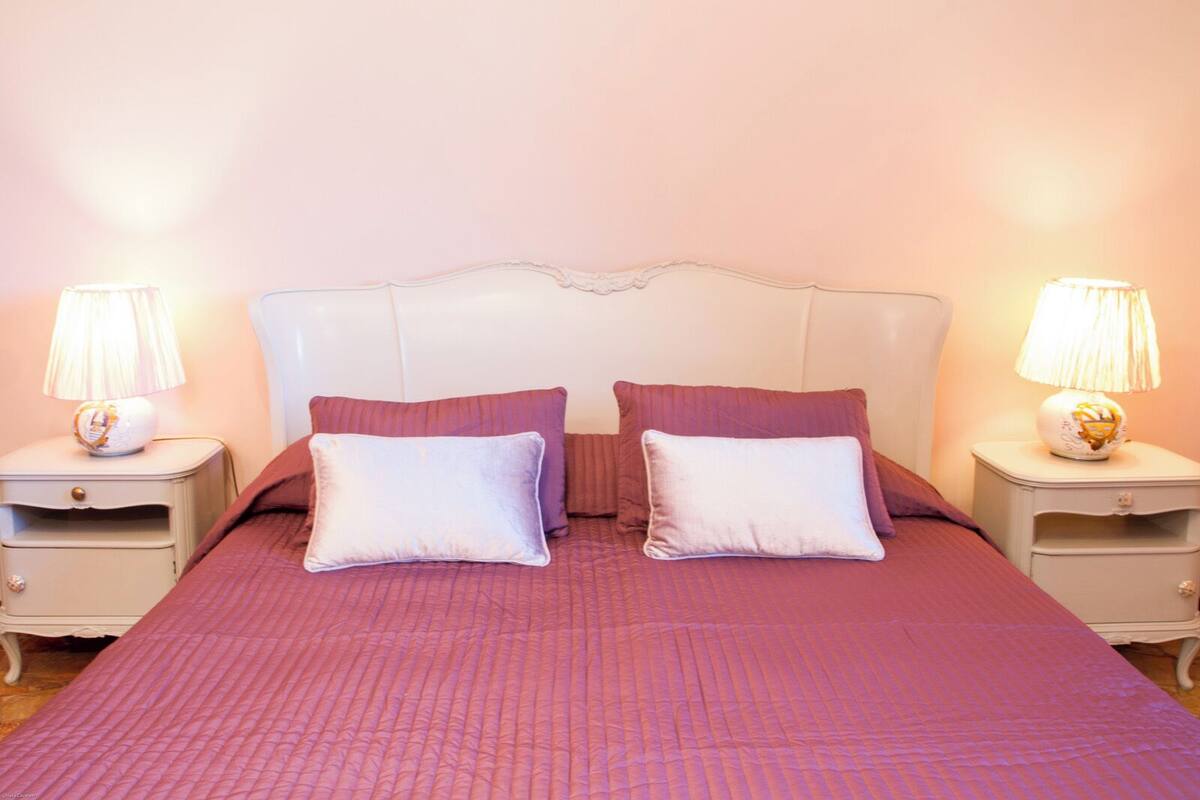 A bed with a headboard, two pillows, and two bedside tables with lamps.