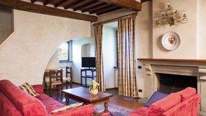 A cozy living room with red sofas, a wooden coffee table, and a fireplace. - Relais de Ricci (Impruneta)