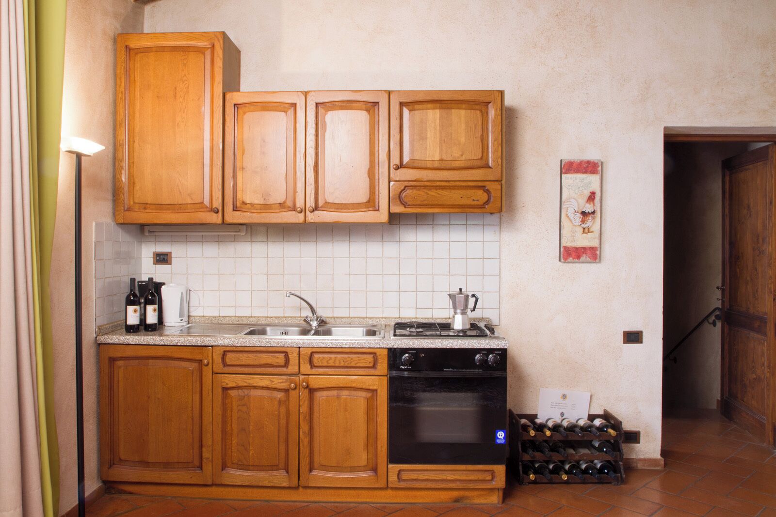 Una cocina con armarios de madera, un fregadero, una estufa y una bodega.