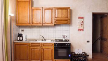 Una cocina con armarios de madera, un fregadero, una estufa y una bodega.