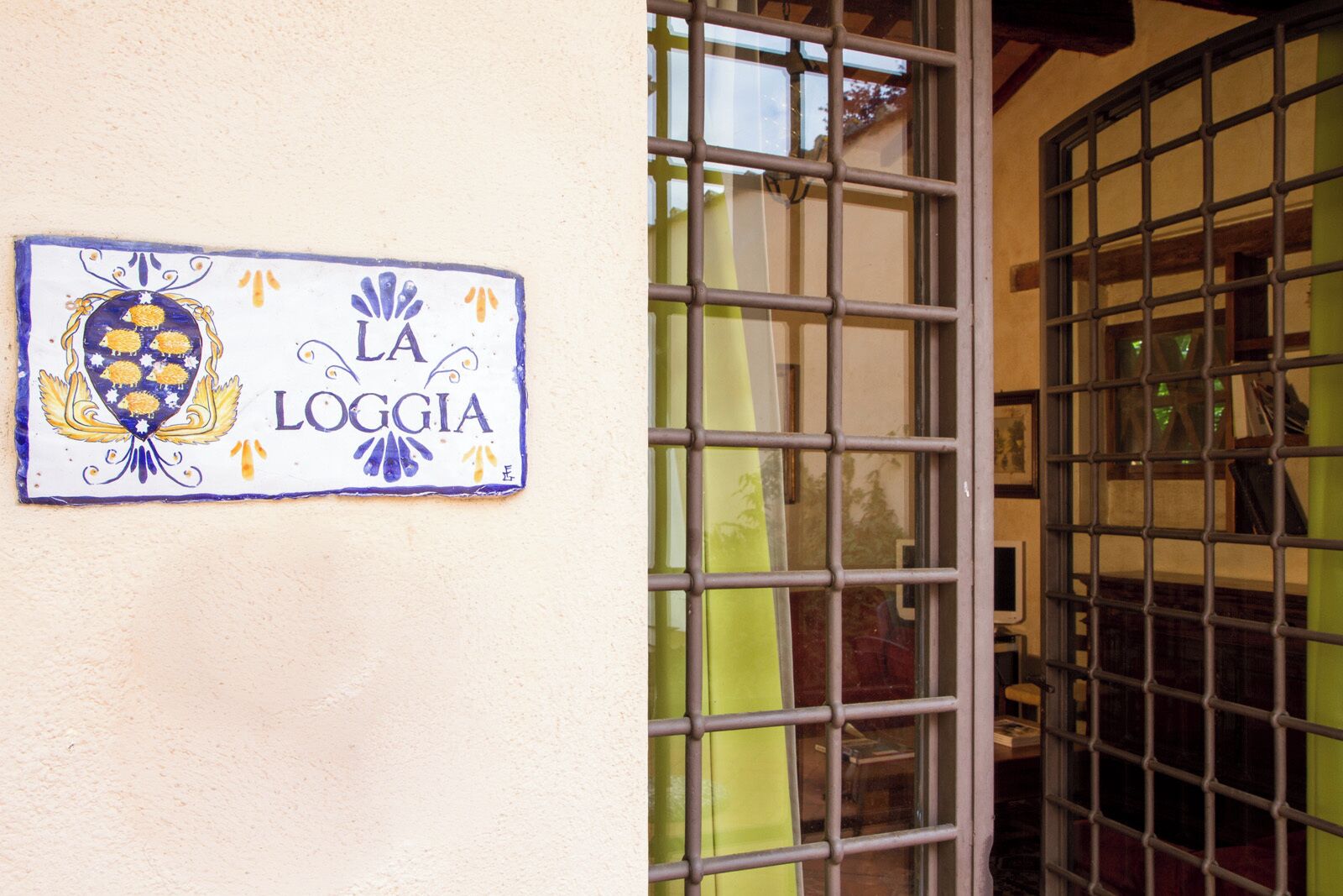 A sign with the text "LA LOGGIA" on a wall, next to a metal gate.