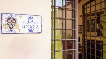 A sign with the text "LA LOGGIA" on a wall, next to a metal gate.