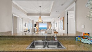 A kitchen with a double sink, granite countertops, and a view to the living area. - Huge Balcony-Spectacular Views-Penthouse 4BR/4Bath (Panama City Beach)