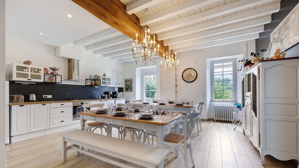 A spacious kitchen with white cabinetry, a wooden dining table set for six, and a large chandelier. - Gîte La Ferme Du Mesnil with Private Terrace, Wi-Fi, and Air Conditioning (Sèvremont)