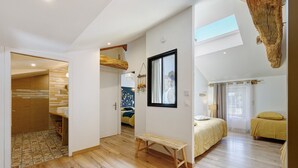 A bedroom with a skylight, a wooden bench, and a bed with yellow bedding. - Gîte La Ferme Du Mesnil with Private Terrace, Wi-Fi, and Air Conditioning (Sèvremont)