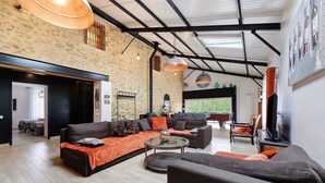 A spacious living area with a large sofa set, a coffee table, and a television. - Gîte La Ferme Du Mesnil with Private Terrace, Wi-Fi, and Air Conditioning (Sèvremont)
