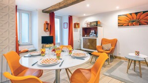 Een eetruimte met een ronde tafel, oranje stoelen en een ontbijt opstelling.