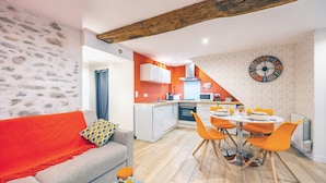 Een moderne woonkamer met een bank, een eettafel met stoelen, een keuken met kasten en een klok aan de muur.
