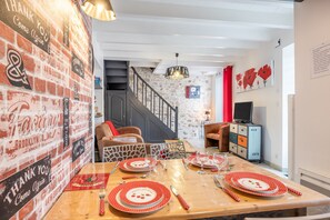 A dining area with a brick wall, a staircase, and a television. - Holiday Home 'Le Clemenceau' with Wi-Fi (Les epesses)