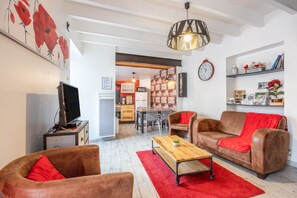 A living room with a TV, two sofas, a coffee table, and a red rug. - Holiday Home 'Le Clemenceau' with Wi-Fi (Les epesses)
