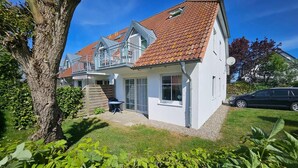 Une maison à deux étages, avec un toit en tuiles, un balcon et une antenne parabolique.