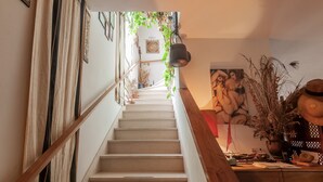 A staircase with a wooden handrail, a white wall with framed artwork, and a potted plant on the landing. - Casa Bice Room with Private Terrace and Wi-Fi (Marcialla)